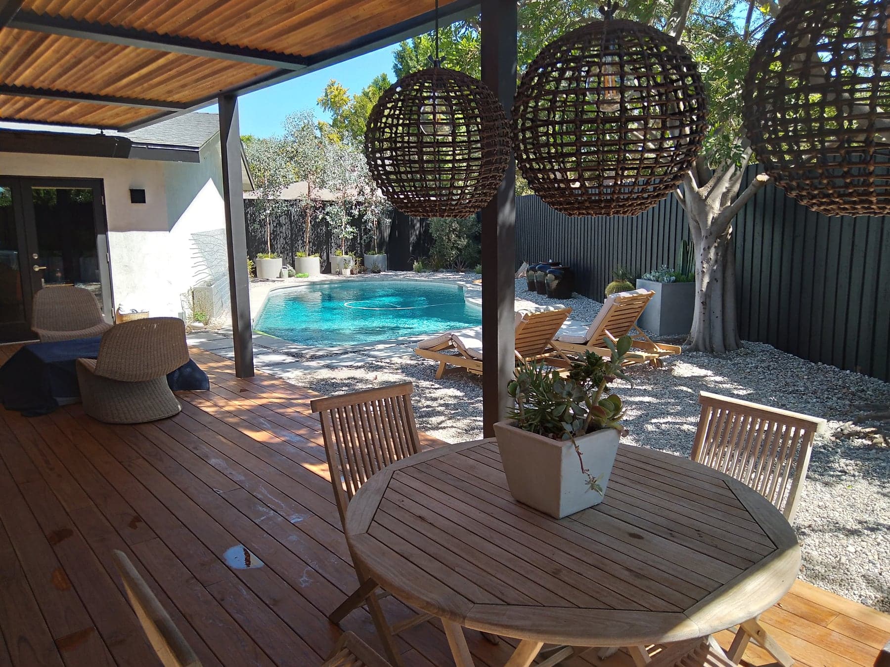 Completed outdoor living project with wood decking, patio cover, and pool